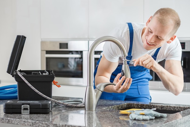 Un homme utilise un filtre à eau pour réparer un évier.