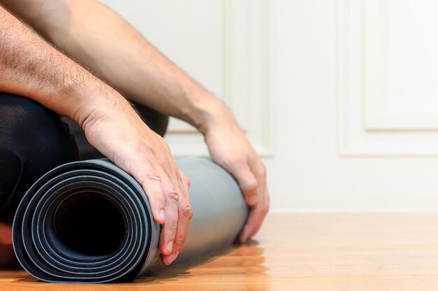 L'homme utilise ses mains pour rouler le yoga vert