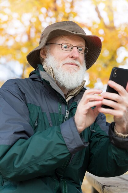 Photo un homme utilise un téléphone portable contre un arbre.