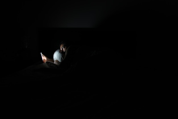 Photo un homme utilise un téléphone portable dans la chambre noire.