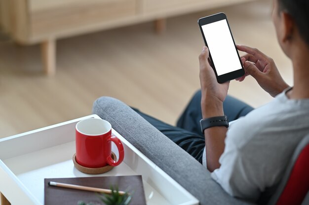 Un homme utilise un téléphone portable et se détend sur un canapé à la maison