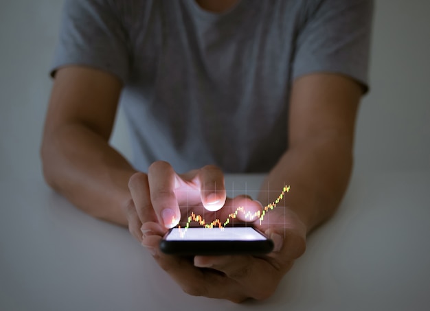 Un homme utilise la vérification d'un graphique d'entreprise avec une technologie de smartphone à écran tactile