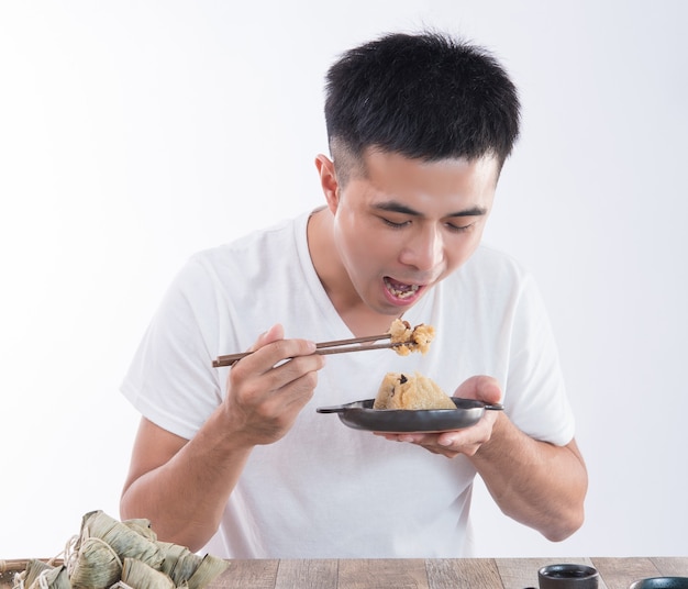 Un homme va manger de délicieux zongzi (boulette de riz) sur Dragon Boat Festival, cuisine traditionnelle asiatique, fond blanc