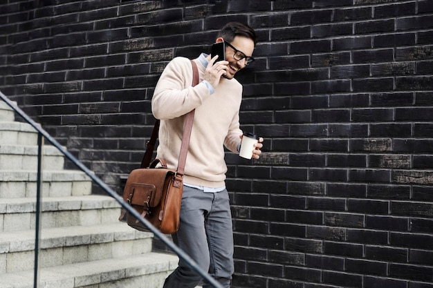 Un homme va travailler au téléphone et boit du café à emporter