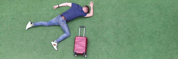 Homme avec valise allongé sur la vue de dessus de l'herbe verte