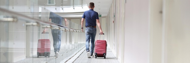 Homme avec valise descendant dans le couloir de l'hôtel vue arrière