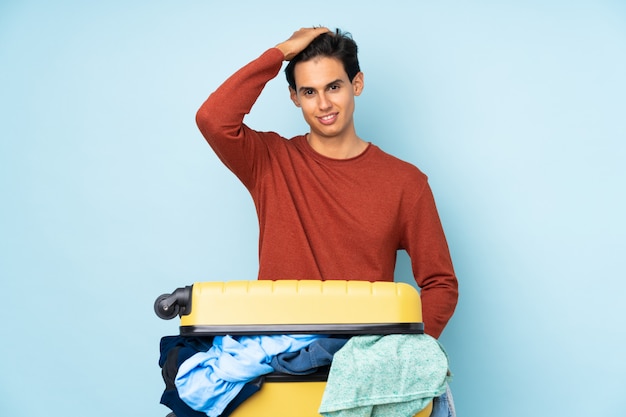 Homme avec une valise pleine de vêtements en riant