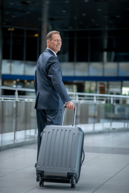 L'homme avec la valise s'est tourné en souriant à la caméra