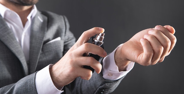 Homme vaporisant du parfum à la main.