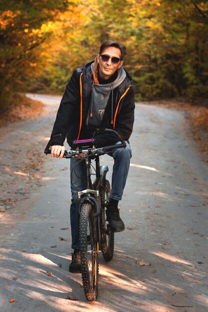 Homme sur un vélo dans la forêt d'automne le soir au coucher du soleil