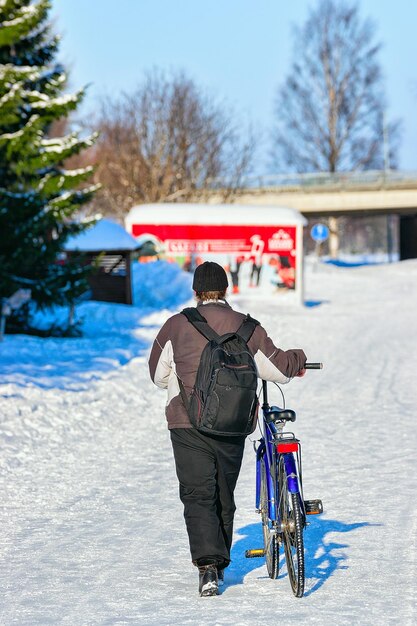 Homme avec un vélo dans la rue enneigée de l'hiver Rovaniemi, Laponie, Finlande.