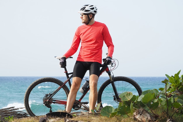 Homme avec un vélo se dresse au bord de l'océan