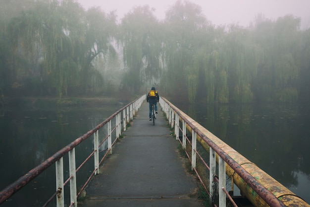 Homme à vélo sur un vieux pont rouillé sur un lac
