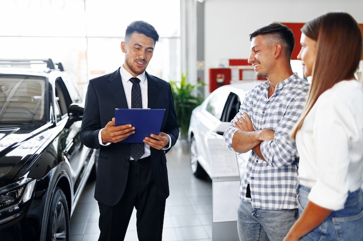 Photo homme vendeur de voitures racontant les caractéristiques de la nouvelle voiture au couple