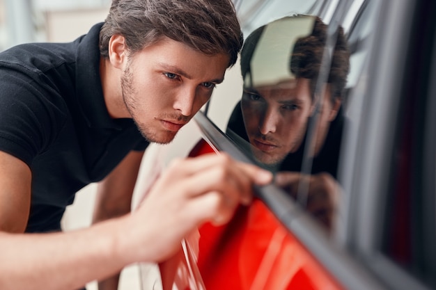 Homme vérifiant la nouvelle voiture chez le concessionnaire