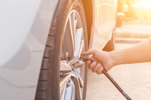 Homme vérifiant la pression de l&#39;air et remplissant les pneus de sa voiture