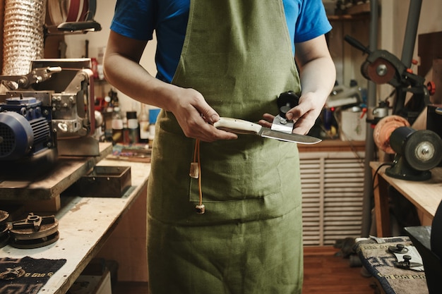 Homme vérifiant si le couteau est tranchant dans l'atelier