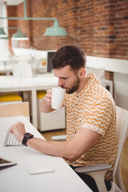 Homme vérifiant le temps tout en prenant un café