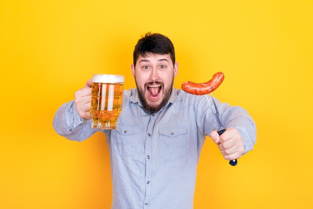 Homme avec un verre de bière et saucisse grillée