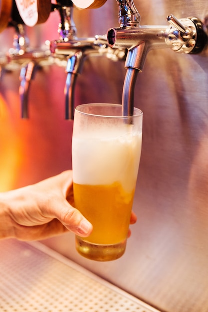 Homme versant de la bière artisanale à partir de bière robinets en verre congelé avec de la mousse.