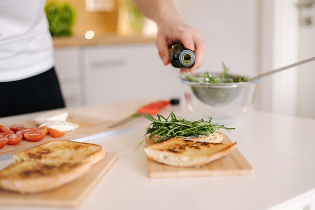 Un homme versant de l'huile de lin pressée à froid sur une bruschetta italienne classique, une nourriture végétalienne et saine.