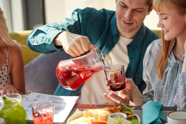 Homme verse une boisson sucrée dans des verres pour femme au café léger