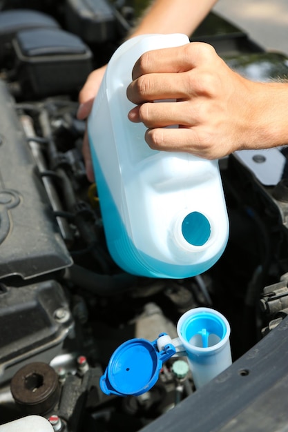 L'homme verse du liquide pour laver les verres dans la voiture