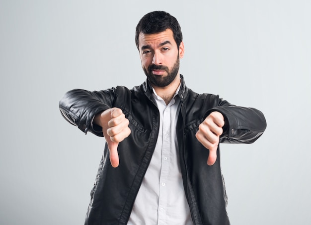 Un homme avec une veste en cuir faisant un mauvais signal