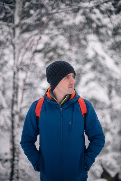 Homme en veste d'hiver marchant dans la forêt d'hiver enneigée journée d'hiver enneigée