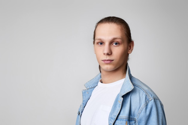 Homme en veste de jeans et t-shirt blanc en regardant la caméra.