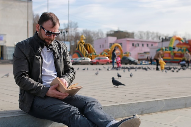 Homme en veste et livre de lecture de rue