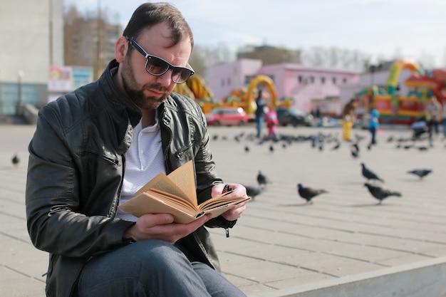 Homme en veste et livre de lecture de rue