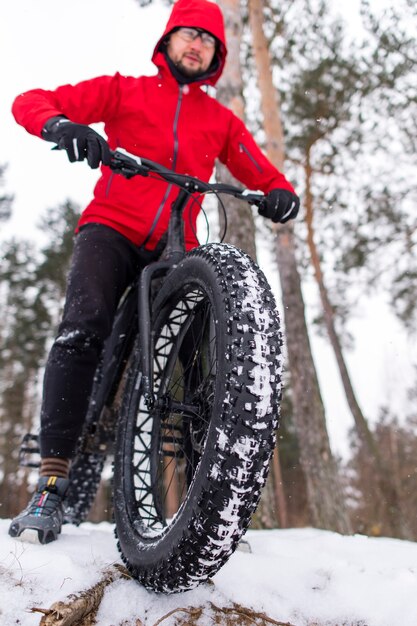 L'homme en veste rouge est assis sur le fatbike en hiver