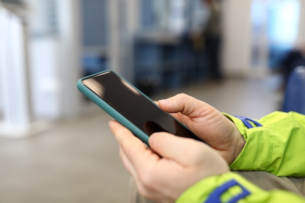 Photo homme en veste de travail en attente, regardant le téléphone.