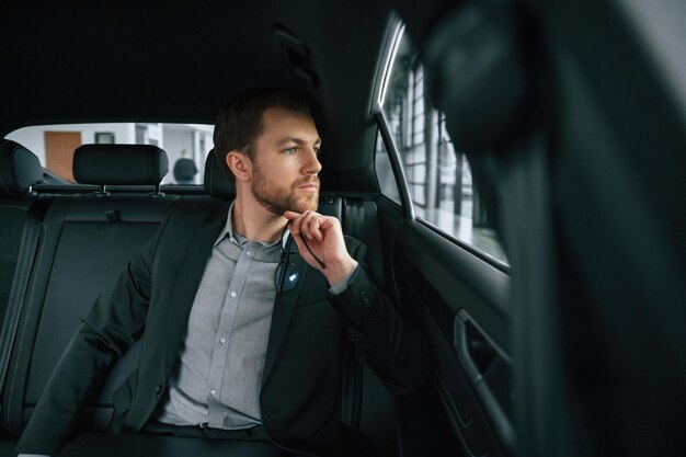 Un homme en vêtements d'affaires formels est assis dans l'automobile moderne