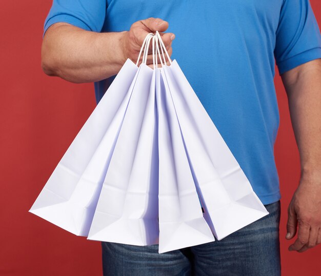 L'homme en vêtements bleus tient une pile de sacs en papier