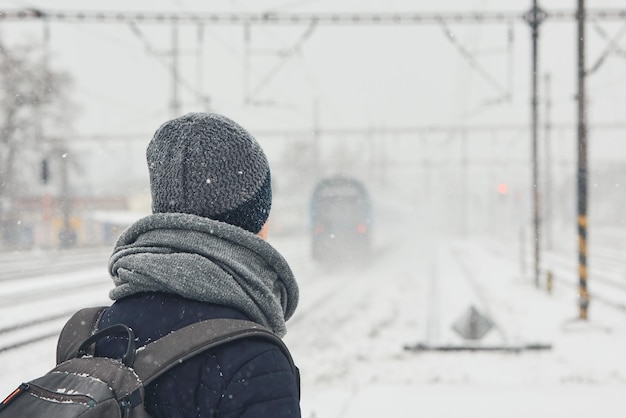 Un homme en vêtements chauds debout sur la plate-forme de la gare