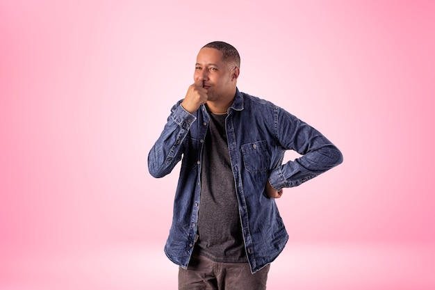 Homme en vêtements courts portant une chemise en jean, un t-shirt blanc et un pantalon marron en photo de studio sur un fond avec des lumières.