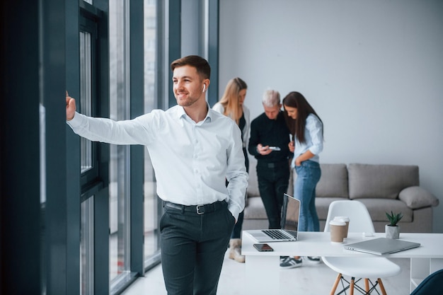 Homme en vêtements formels debout devant une jeune équipe réussie qui travaille et communique ensemble à l'intérieur au bureau