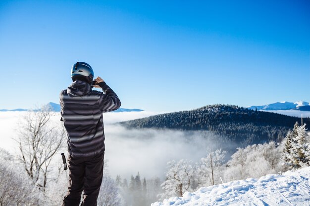 Homme en vêtements d'hiver prenant un selfie avec des montagnes