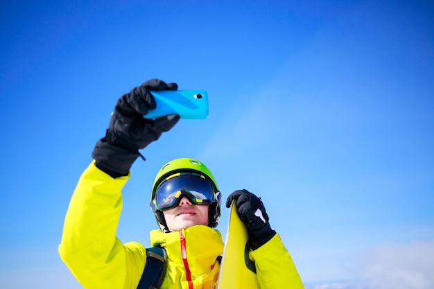 Homme en vêtements d'hiver prenant un selfie avec des skis