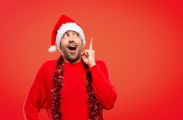 Homme avec des vêtements rouges célébrant les vacances de Noël debout et pensant à une idée