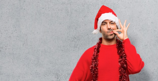 Homme avec des vêtements rouges, célébrant les vacances de Noël, montrant un signe de fermeture de la bouche