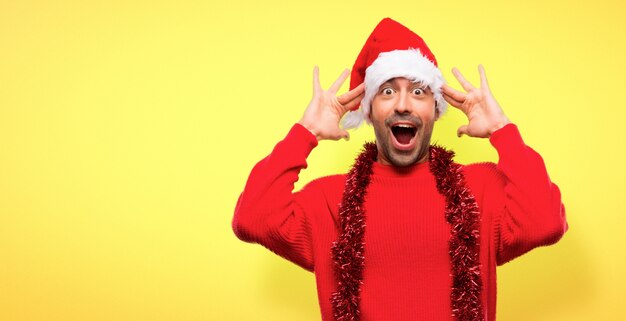 Homme avec des vêtements rouges célébrant les vacances de Noël avec surprise et choqué