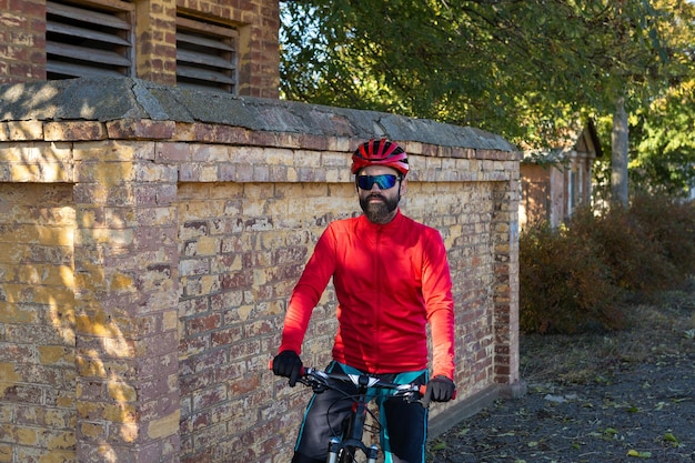 Un homme en vêtements se tient avec un vélo sur une journée ensoleillée d'automne Cycliste dans un environnement urbain