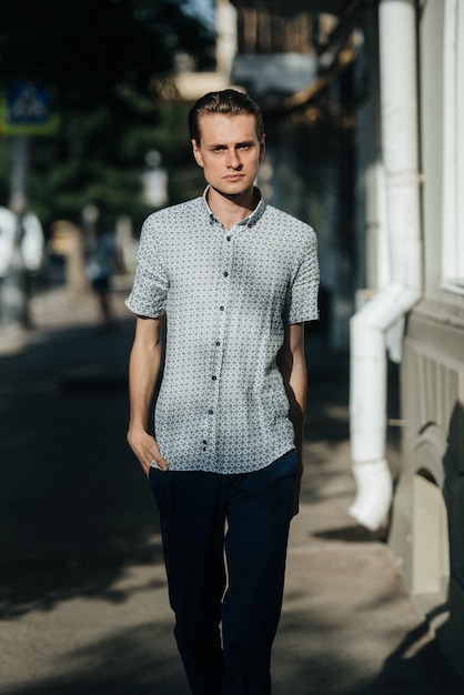 Un homme vêtu d'une chemise à carreaux blanche et d'un pantalon bleu pose pour la publicité de vêtements pour hommes. Prise de vue pour magasin de vêtements pour hommes