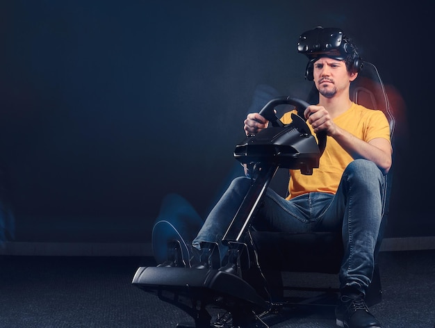 Homme vêtu d'une chemise jaune et d'un jean portant un casque VR conduisant sur le cockpit du simulateur de course automobile avec siège et roue.