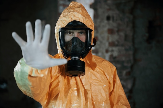 Homme vêtu d'une combinaison de protection chimique dans les ruines du bâtiment post-apocalyptique