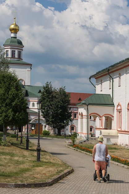 Homme vêtu de façon décontractée marchant avec un landau à l'église orthodoxe de la ville de Tikhvin