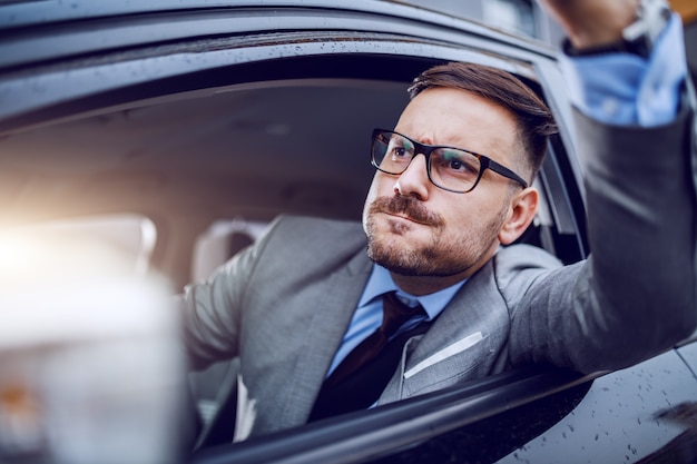 Un homme vêtu vif se retrouvant pris dans une heure de pointe et succombant lentement à la rage au volant.